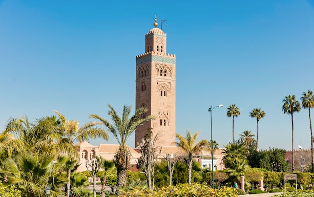 Koutoubia Mosque tower surrounded by palm trees in Marrakesh.