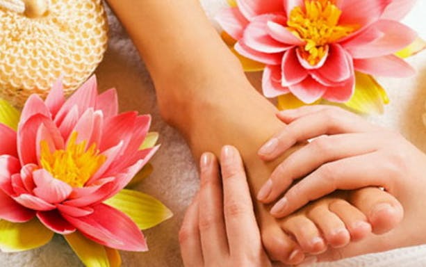 Japanese foot massage with hands applying pressure, surrounded by pink lotus flowers.