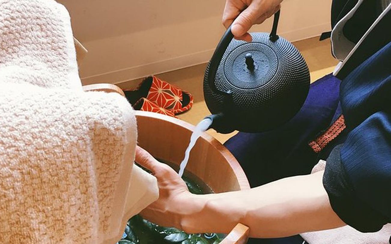 Pouring water into a wooden basin for Arashiyu Japanese foot massage.