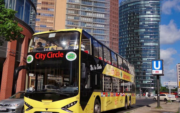 City Circle sightseeing bus in Berlin near modern buildings and U-Bahn sign.