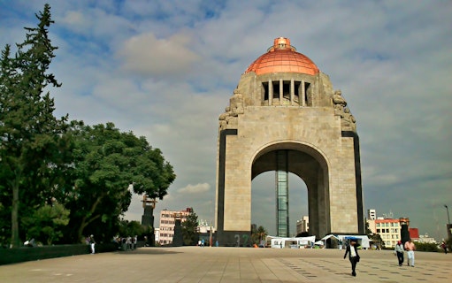 Monument to the Revolution in Mexico City with visitors walking nearby.