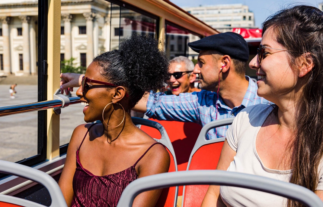 Tourists enjoying a ride on the Big Bus Berlin, passing by historic buildings.