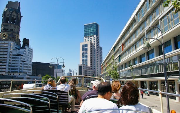 Open-top bus tour passing Kaiser Wilhelm Memorial Church in Berlin.