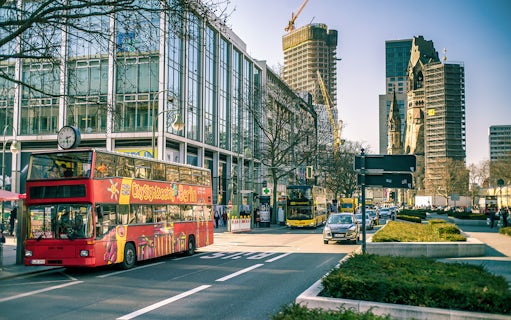 City sightseeing bus in Berlin with Kaiser Wilhelm Memorial Church in background.