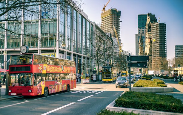 City sightseeing bus in Berlin with Kaiser Wilhelm Memorial Church in background.