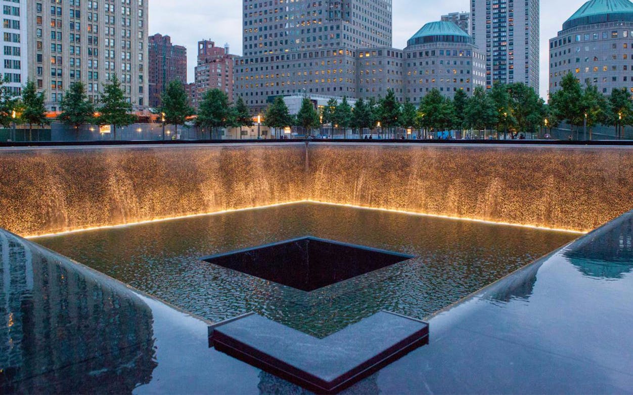 9/11 Memorial reflecting pool with city buildings in New York City.