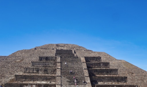 Visitors climbing the Pyramid of the Sun at Teotihuacan, Mexico under a clear blue sky.