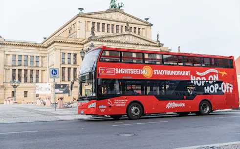 Red double-decker sightseeing bus in front of Konzerthaus Berlin.