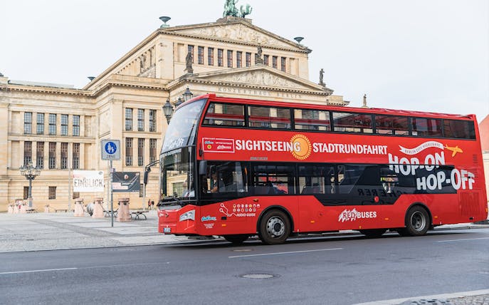 Red double-decker sightseeing bus in front of Konzerthaus Berlin.