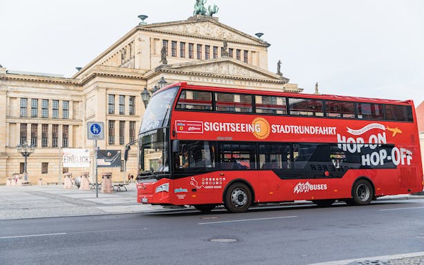 Red double-decker sightseeing bus in front of Konzerthaus Berlin, part of Hop On Hop Off tour.