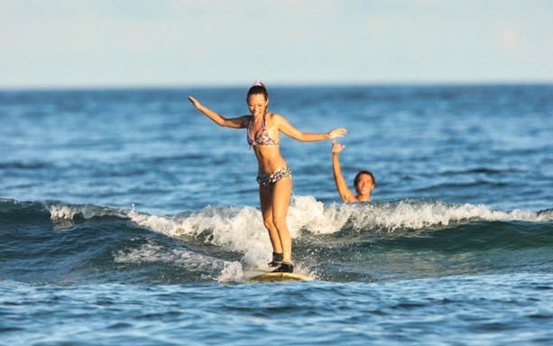 Surfers riding waves in the clear blue sea of Chatan Town, Okinawa.