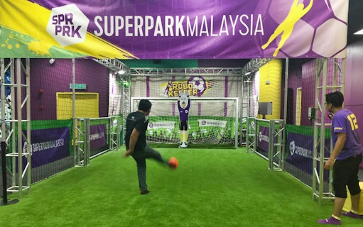 Man playing soccer game at SuperPark Kuala Lumpur indoor activity center.