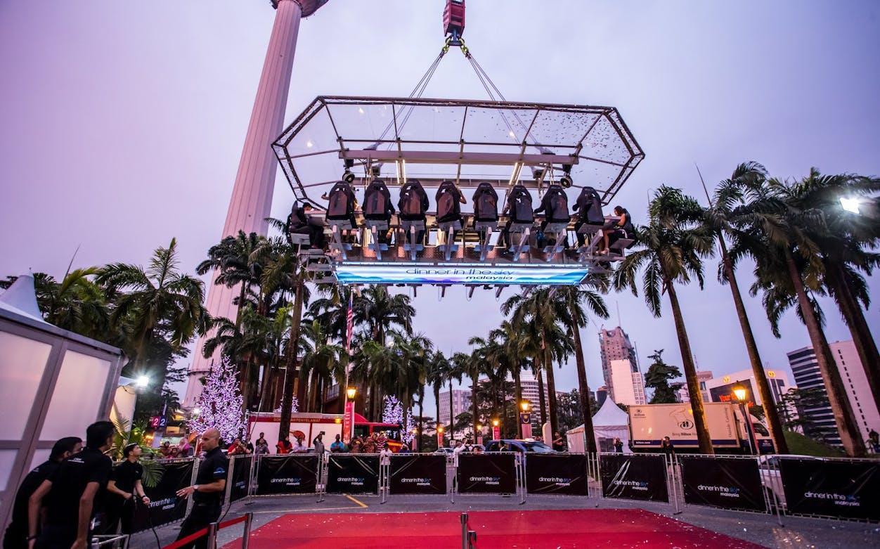 Dinner In The Sky experience in Kuala Lumpur, Malaysia, with diners suspended above the city.