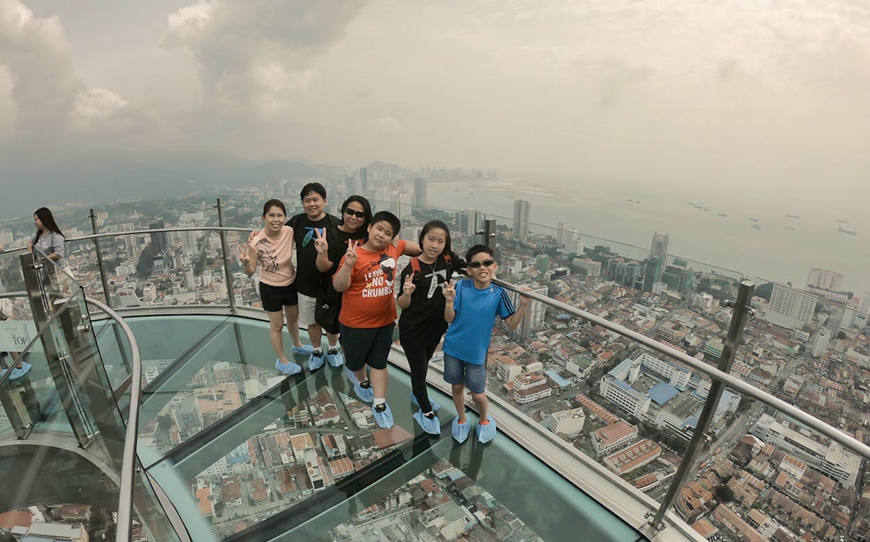 Group on glass skywalk at THE TOP Komtar Penang with city and ocean view.