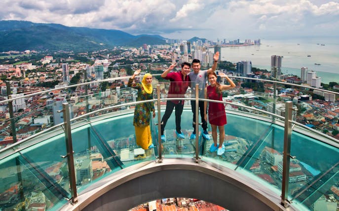 Visitors on the glass skywalk at THE TOP Komtar Penang with city and sea views.