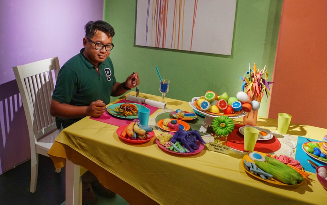 Man seated at a table with colorful food displays at Wonderfood Museum.