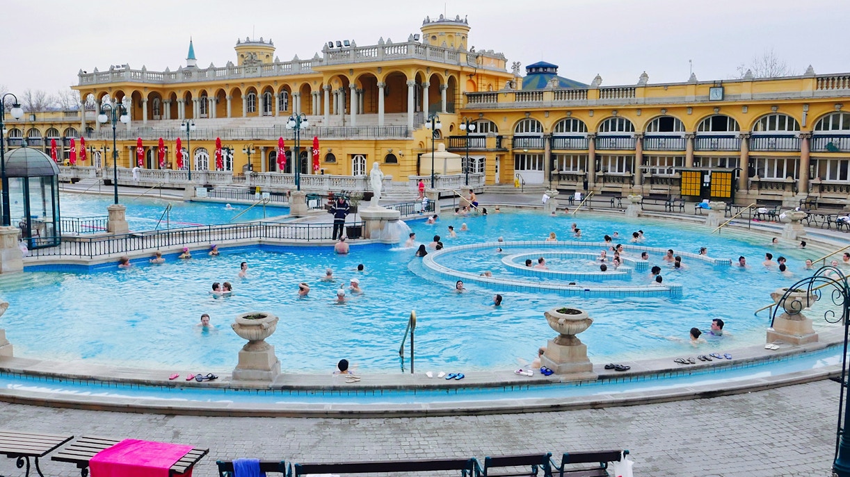 Széchenyi Spa thermal pools in Budapest with tourists relaxing, followed by a Danube River dinner cruise with live music.
