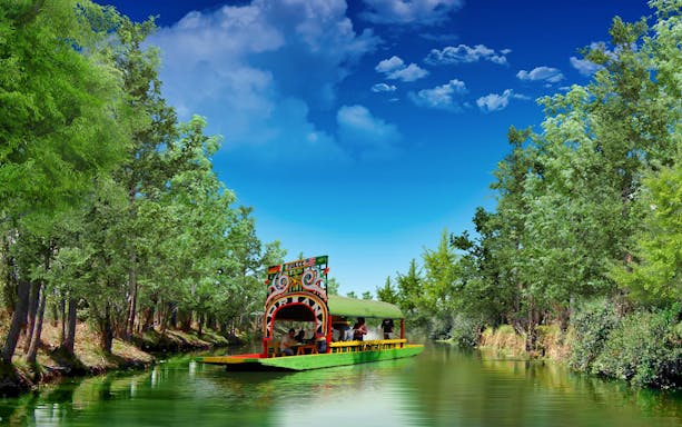 Colorful trajinera boat on Xochimilco canal, surrounded by lush greenery, Mexico City tour.