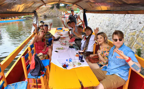 Tourists enjoying a boat ride in Xochimilco, Mexico City, on a guided tour.