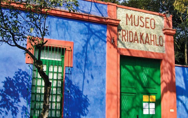 Frida Kahlo Museum entrance in Coyoacan, featuring vibrant blue and red facade.