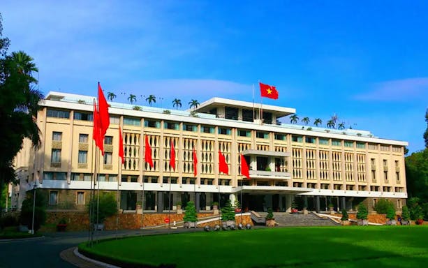 Reunification Palace in Ho Chi Minh City with Vietnamese flags displayed.
