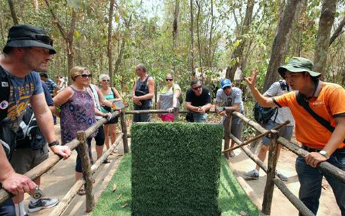 Tour group at Cu Chi Tunnels entrance with guide explaining in Ho Chi Minh.