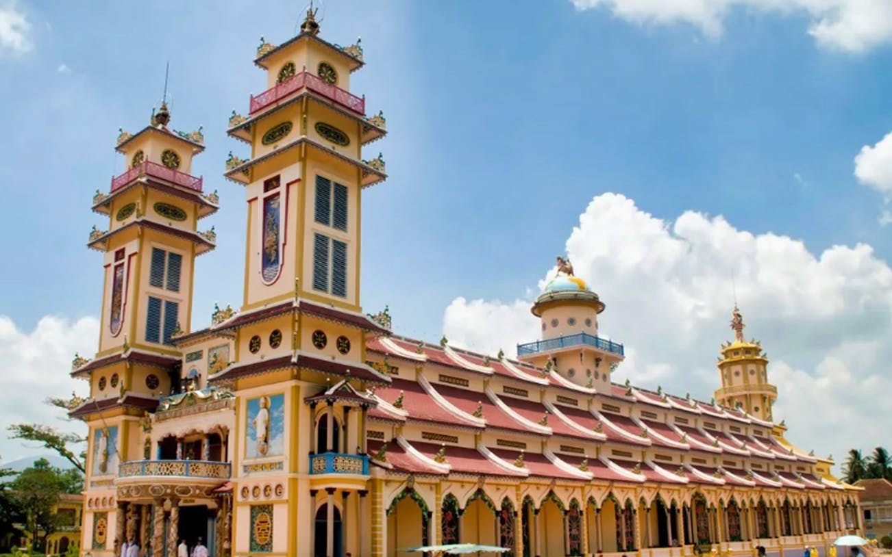 Cao Dai Temple with ornate architecture under a blue sky, part of the Cu Chi Tunnels tour.