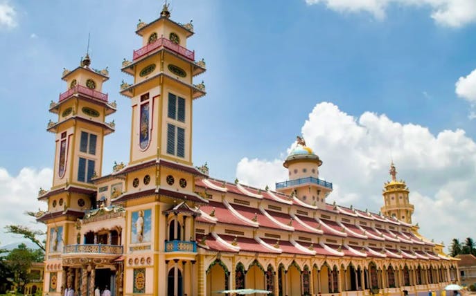 Cao Dai Temple with ornate architecture under a blue sky, part of the Cu Chi Tunnels tour.