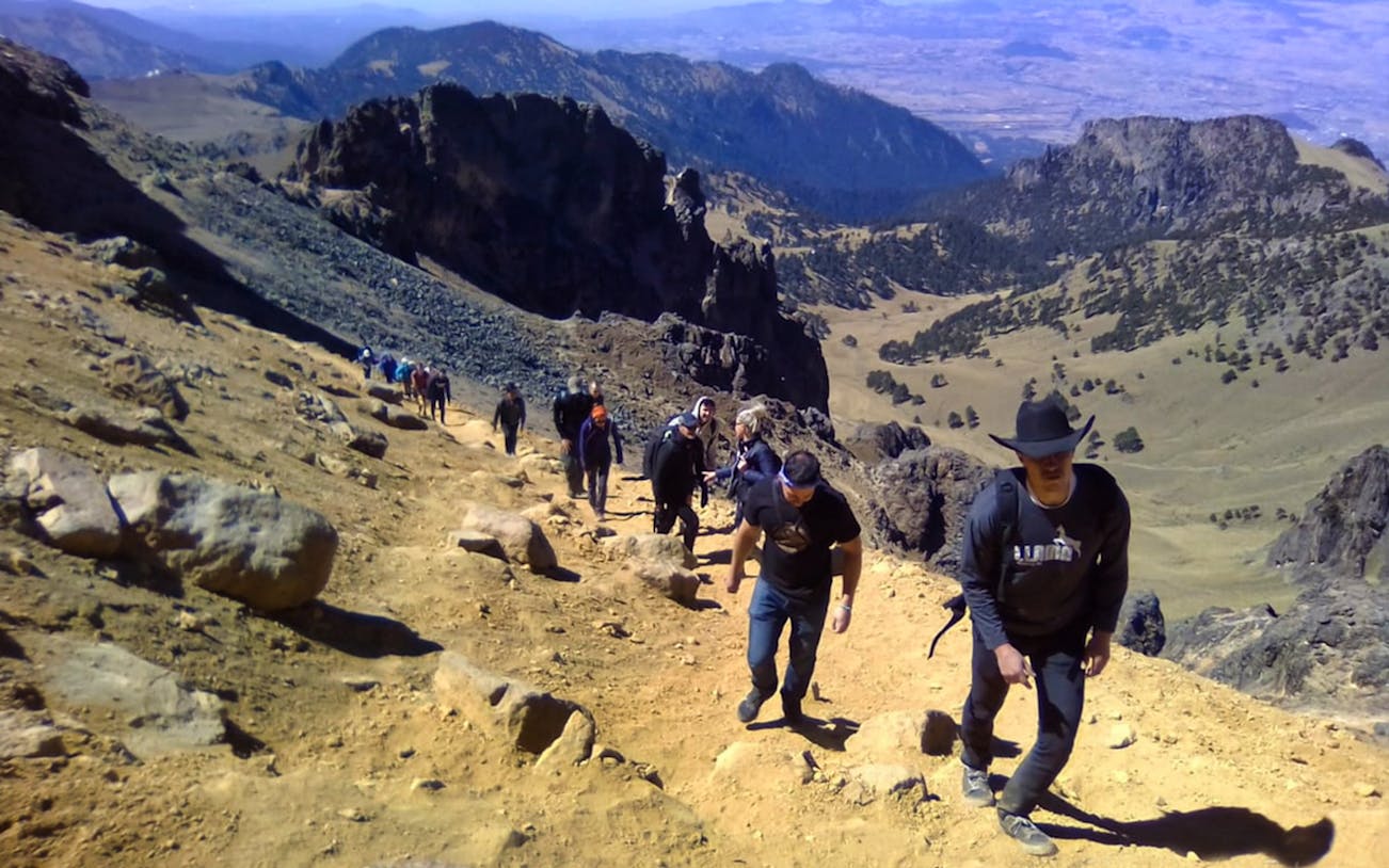 Hikers ascending a rocky trail in Iztaccíhuatl-Popocatépetl National Park.