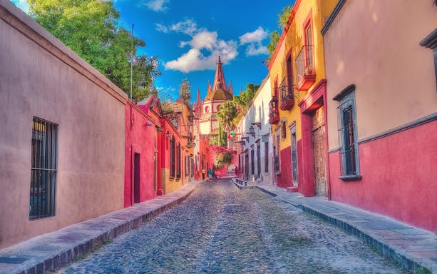 Cobbled street with colorful buildings leading to Parroquia de San Miguel Arcángel in San Miguel de Allende.