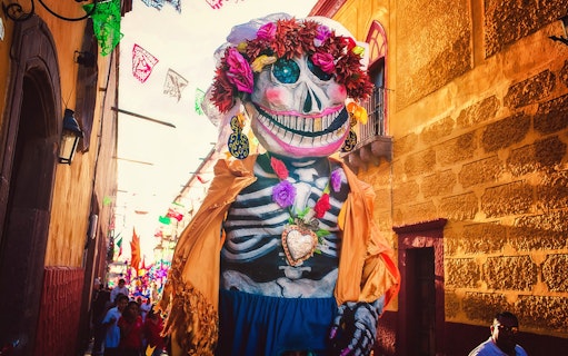 Giant skeleton figure in colorful attire during a festival in San Miguel de Allende.