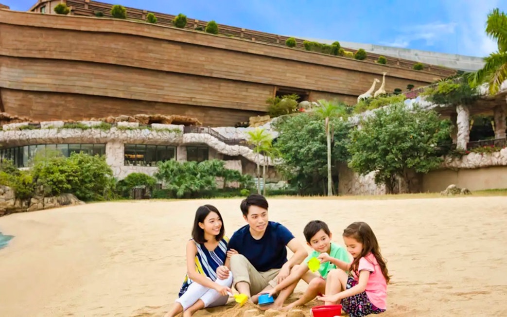 Family playing on the beach in front of Noah's Ark, Hong Kong.