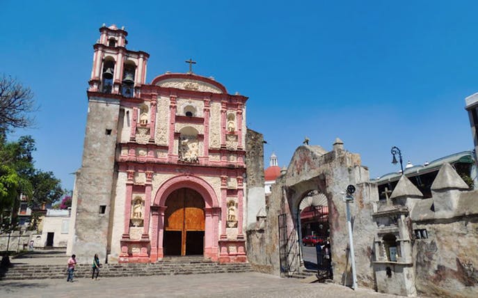 Colonial church facade in Cuernavaca, Mexico, with stone archway and clear blue sky.