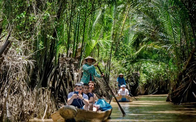 Small boats navigating through lush greenery in the Mekong Delta.