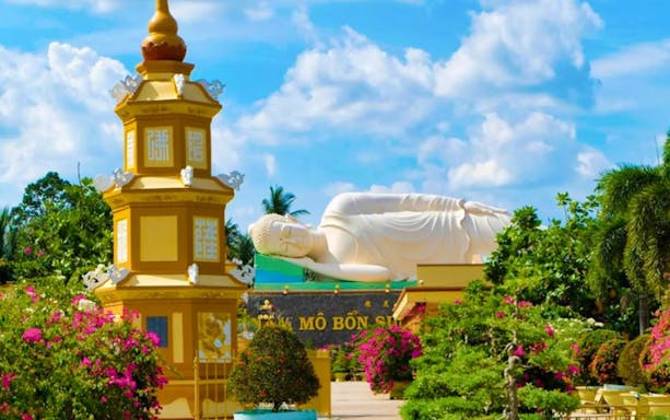 Vinh Trang Pagoda with reclining Buddha statue in Mekong Delta, surrounded by lush gardens.
