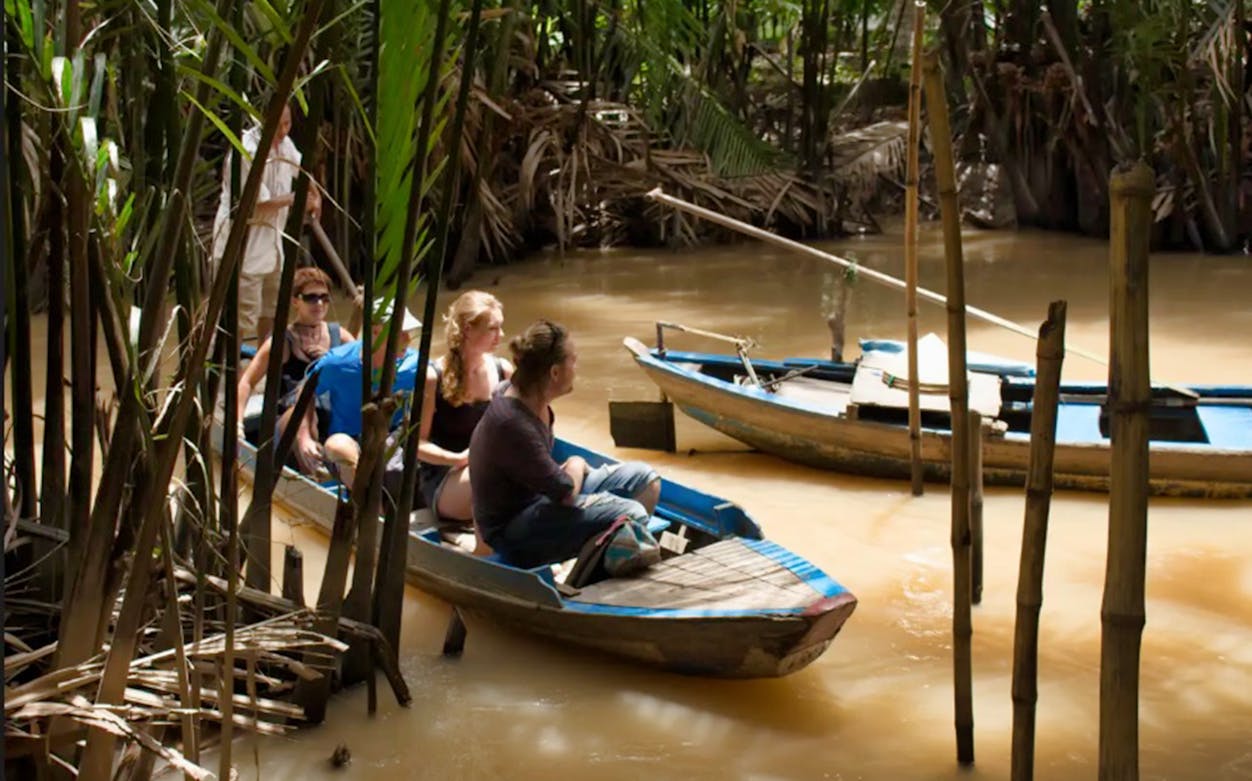 Tourists on a boat navigating the Mekong Delta's narrow waterways.
