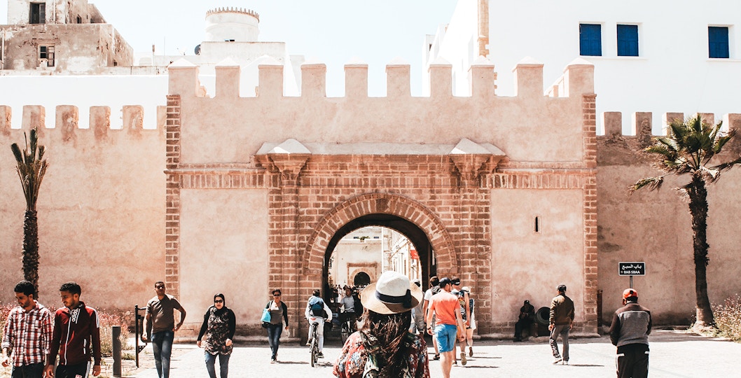 Essaouira city gate with tourists walking, part of Marrakesh day trip.