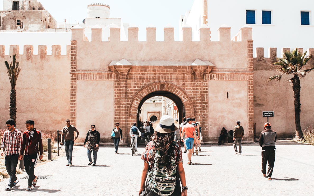Essaouira city gate with tourists walking, part of Marrakesh day trip.