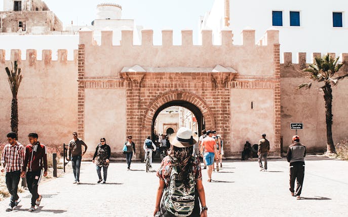 Essaouira city gate with tourists walking, part of Marrakesh day trip.