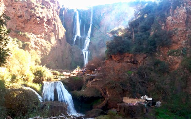 Ouzoud Waterfalls cascading down rocky cliffs in Marrakesh, Morocco, with surrounding greenery.