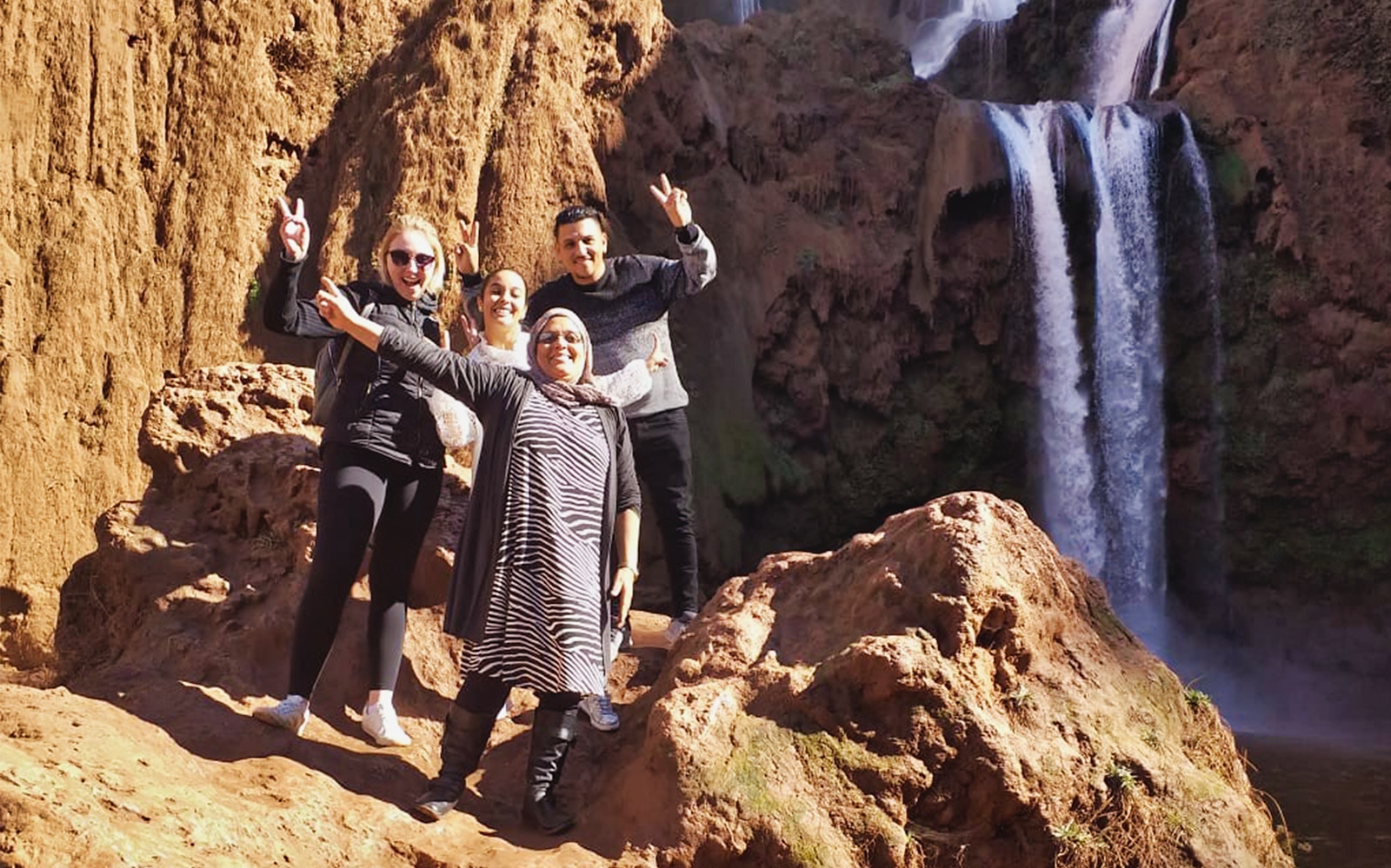 Group of tourists posing near Ouzoud Waterfalls during a day tour from Marrakesh.