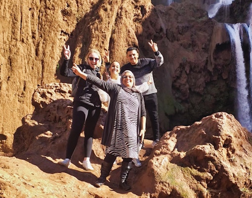 Group of tourists posing near Ouzoud Waterfalls during a day tour from Marrakesh.