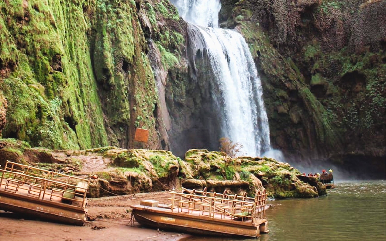 Boats near Ouzoud Waterfalls with lush greenery, part of a day tour from Marrakesh.
