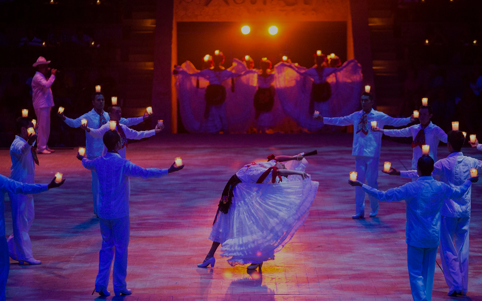 Dancers performing traditional Mexican dance with candles at Xcaret Park night show.