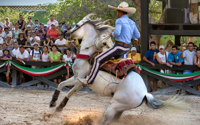 Horseman performing at Xcaret Park with audience watching.