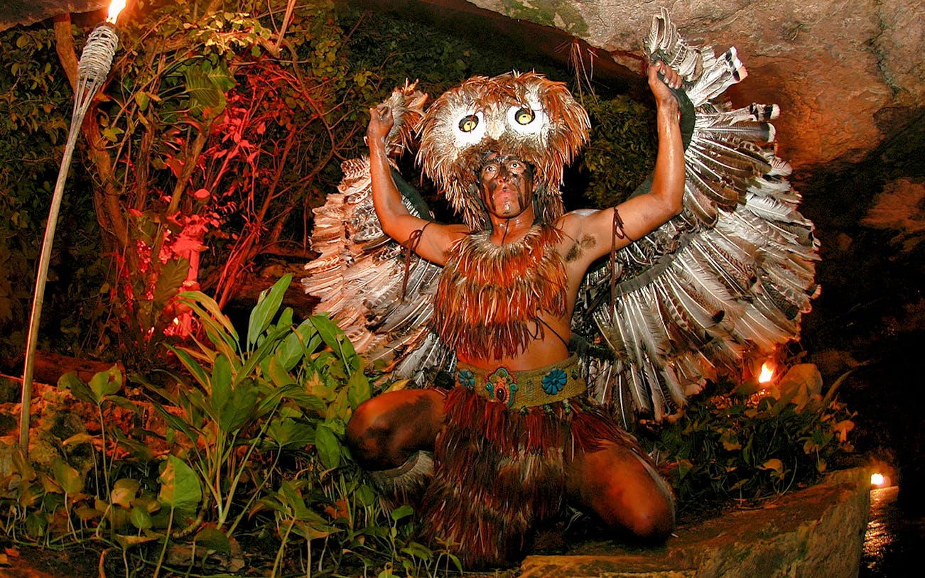Performer in feathered costume at Xcaret night show, Mexico.