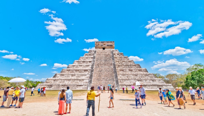 Ancient Chichen Itza pyramid with tourists exploring the site in Cancun, Mexico.