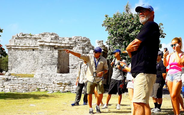 Guide explaining ruins to tourists on Chichen Itza tour.