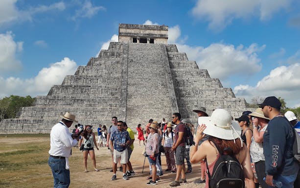 Tour group at Chichen Itza pyramid, Mexico, during guided excursion.