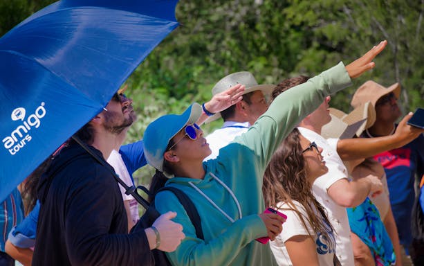 Tourists observing Chichen Itza ruins during guided tour with Amigo Tours.